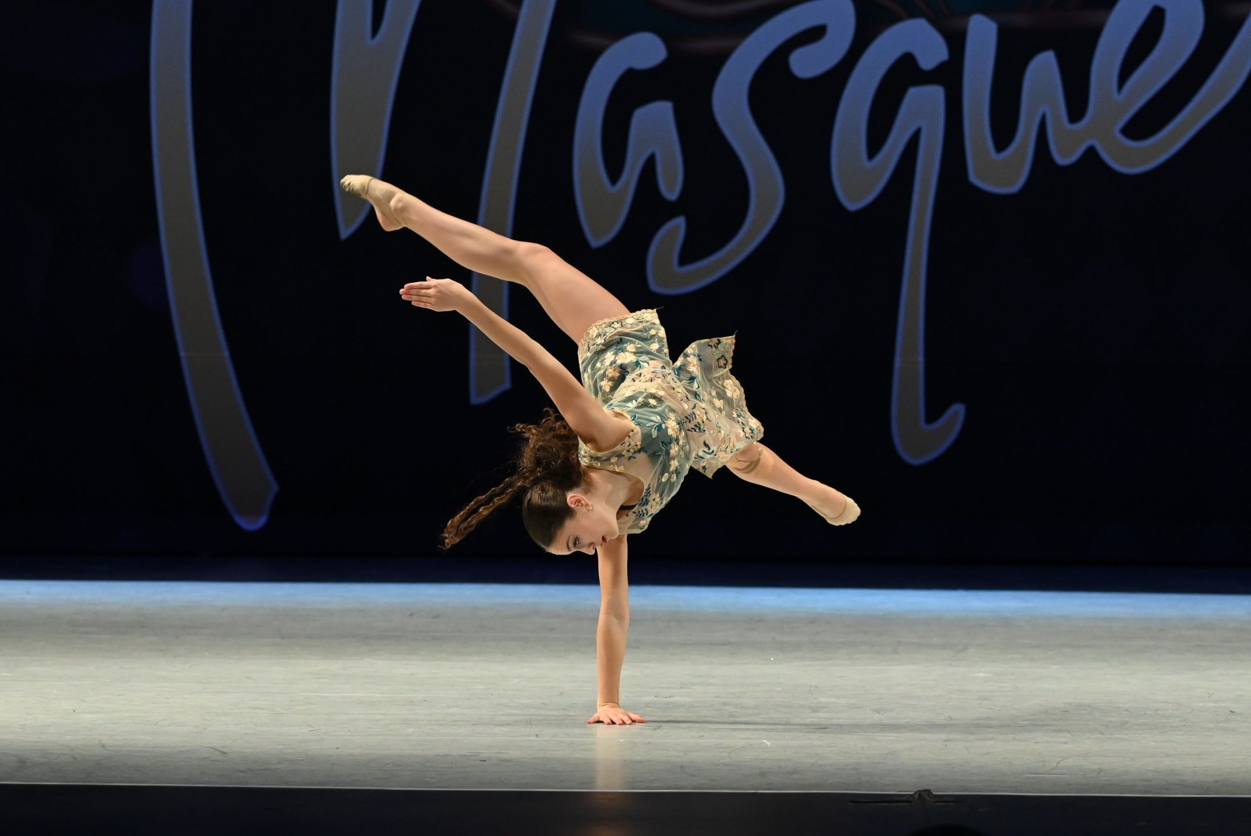 Allison, a competitive dancer, mid-performance in costume under stage light.